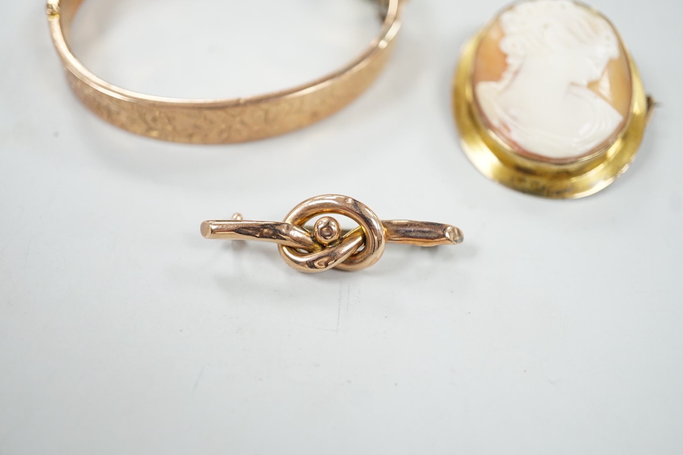 A 9ct mounted oval cameo shell brooch, 41mm, a 9ct gold bangle and a 9ct knot brooch